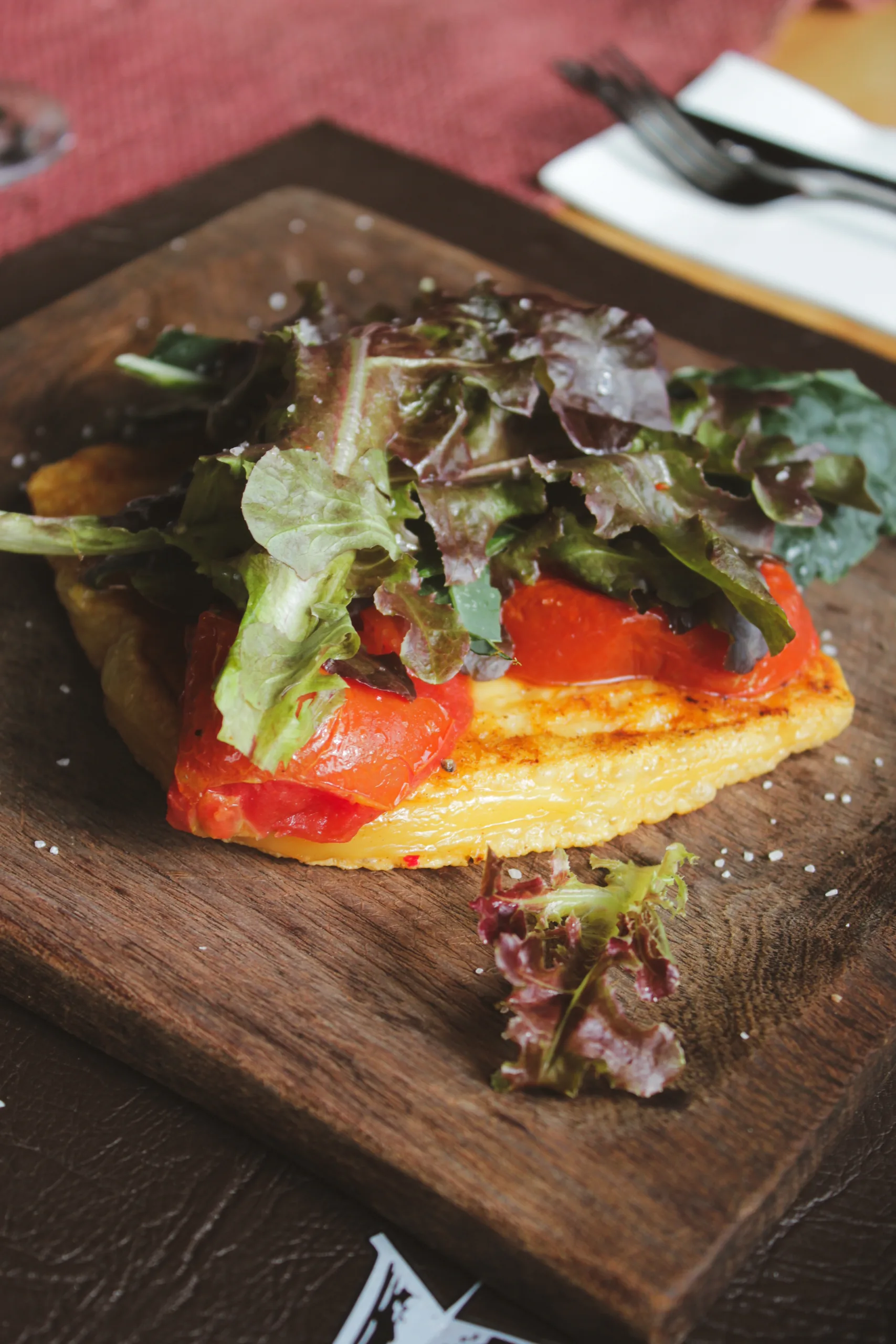 Provoleta con tomate y hojas verdes